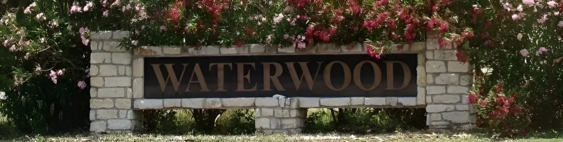 A sign that says waterwood with flowers in the background.