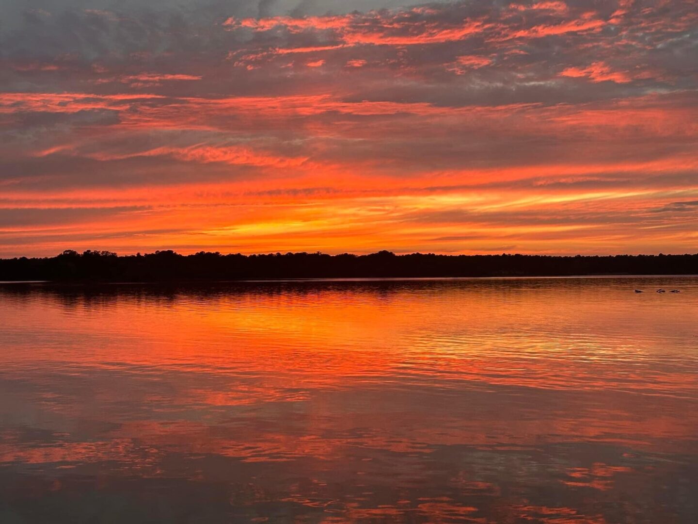 A sunset over the water with some clouds in the sky