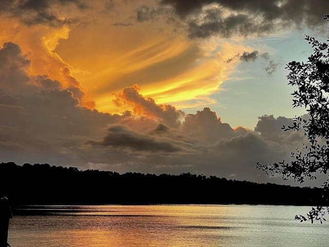 A sunset over the water with clouds in the sky.