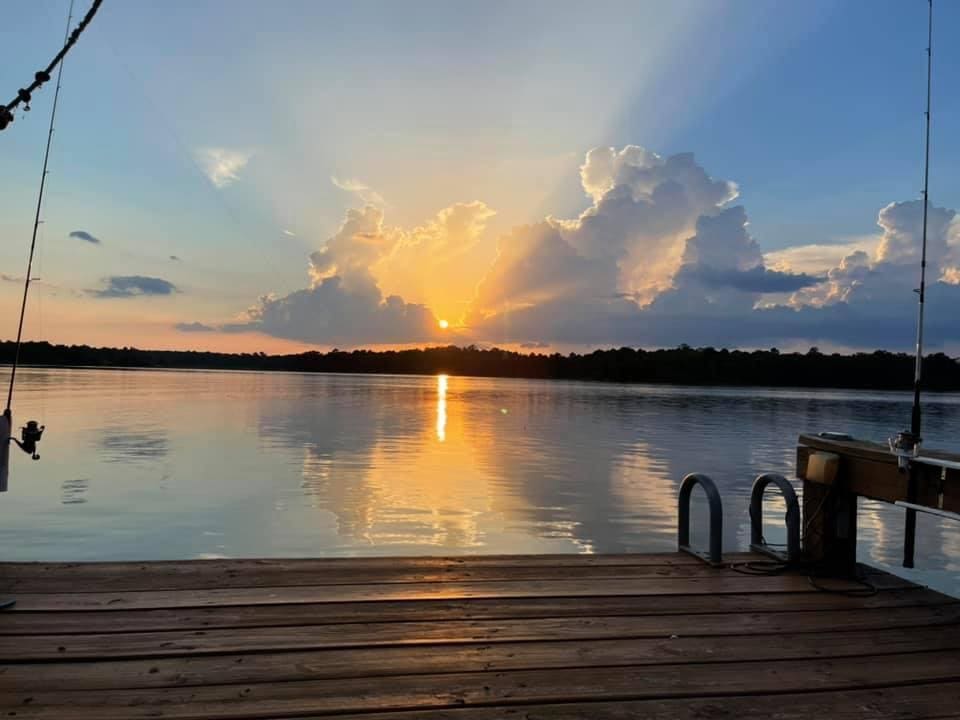 A dock with the sun setting over a body of water.