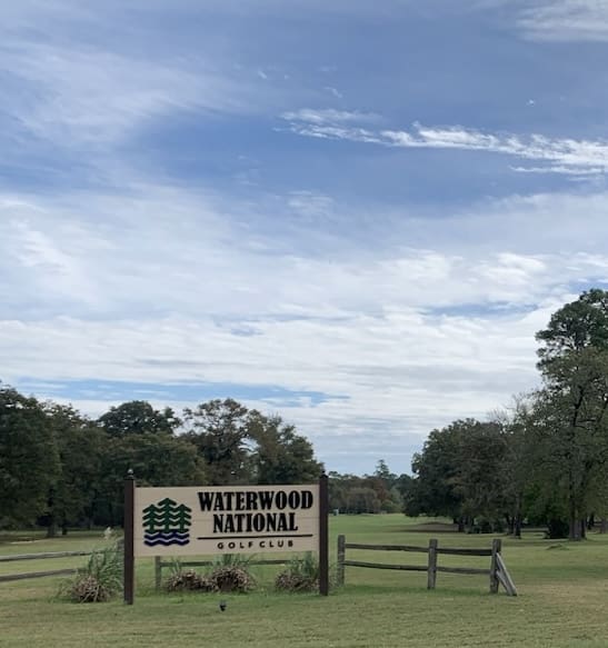 A sign in front of some trees and grass